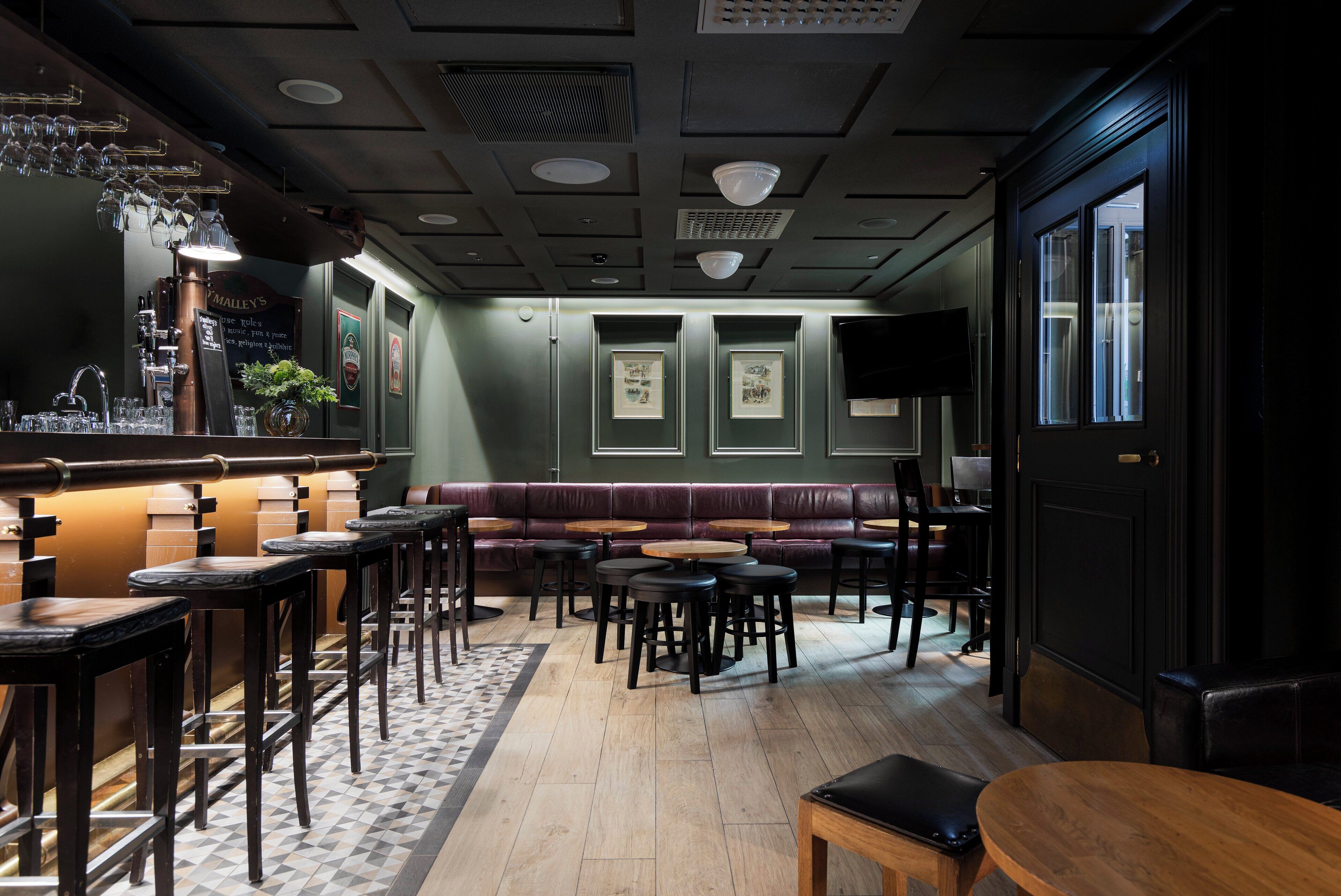 A bar area with stools, tables, and a bar counter.