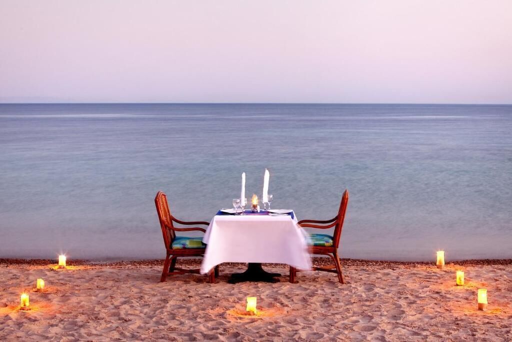 A beachside table set with candles and a white tablecloth, overlooking the sea.