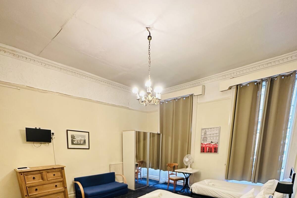 A hotel room with two beds, a desk, a chair, a dresser, a television, and a large mirror.