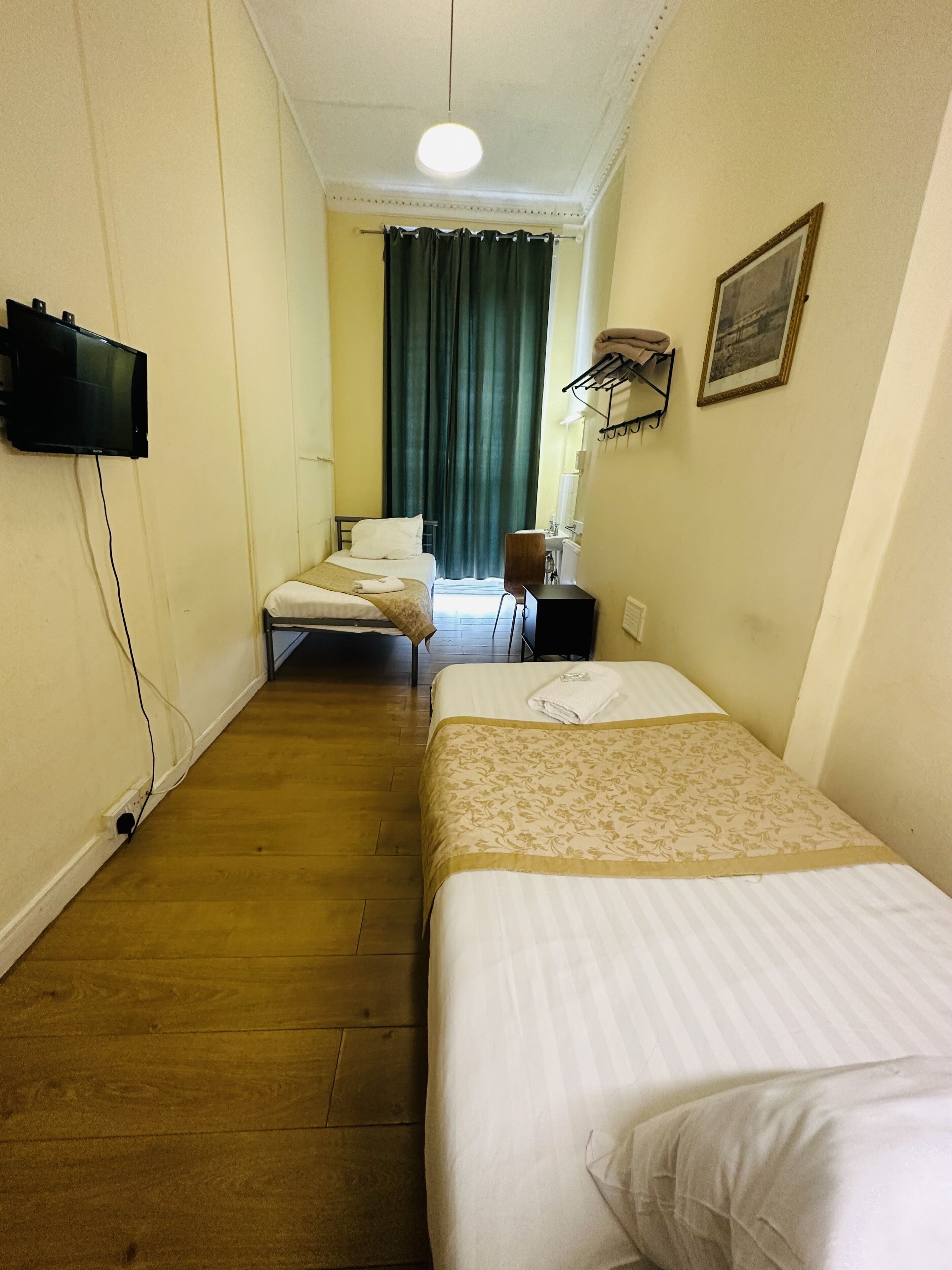 A hotel room with two beds, a television, a desk, and a chair.