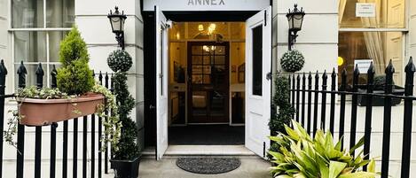 The entrance to Thanet Hotel Annex with a white facade, black iron fence, and potted plants.