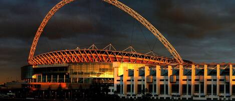 A stadium with a large arch structure, multiple entry points, and a glass facade.