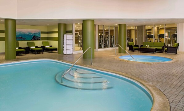 Relax by the oval-shaped pool surrounded by comfortable lounge chairs and a vibrant abstract art piece.