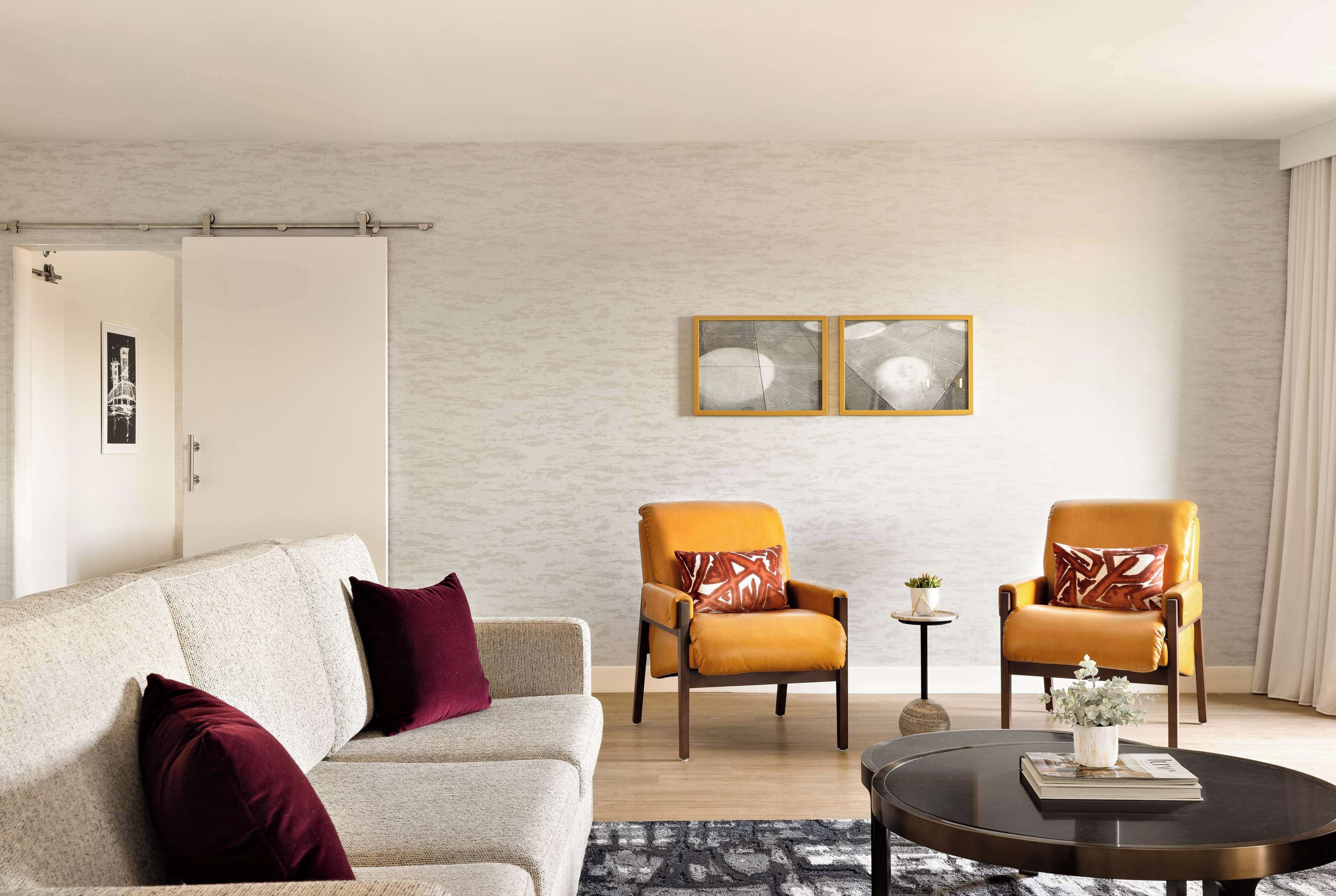 Un salon moderne comprenant un canapé, deux fauteuils, une table basse et une petite table d’appoint agrémentée d’une plante.