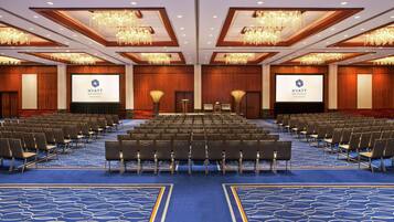 A conference room at the Hyatt Regency New Brunswick with rows of chairs, a stage, and a large screen.