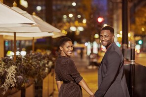 Enjoy a tranquil evening in the city under the stars, surrounded by lush greenery and stylish umbrellas.