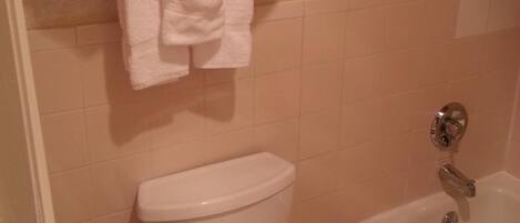 A bathroom with a toilet, a bathtub, and a towel rack with folded towels.