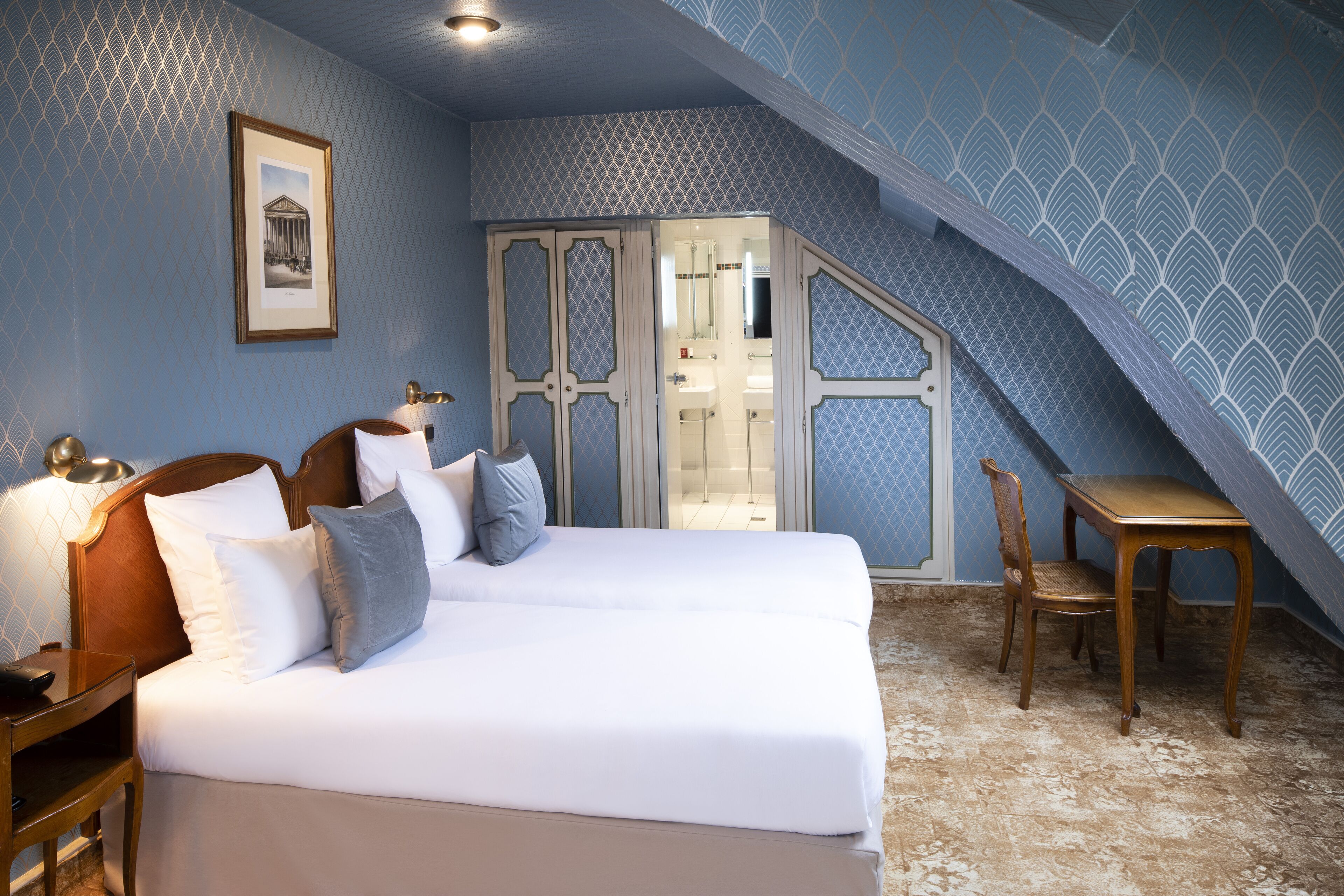 A bedroom with a bed, bedside table, lamp, and a chair.