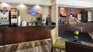 A breakfast counter with coffee machines, a Baymont sign, and a variety of food items.