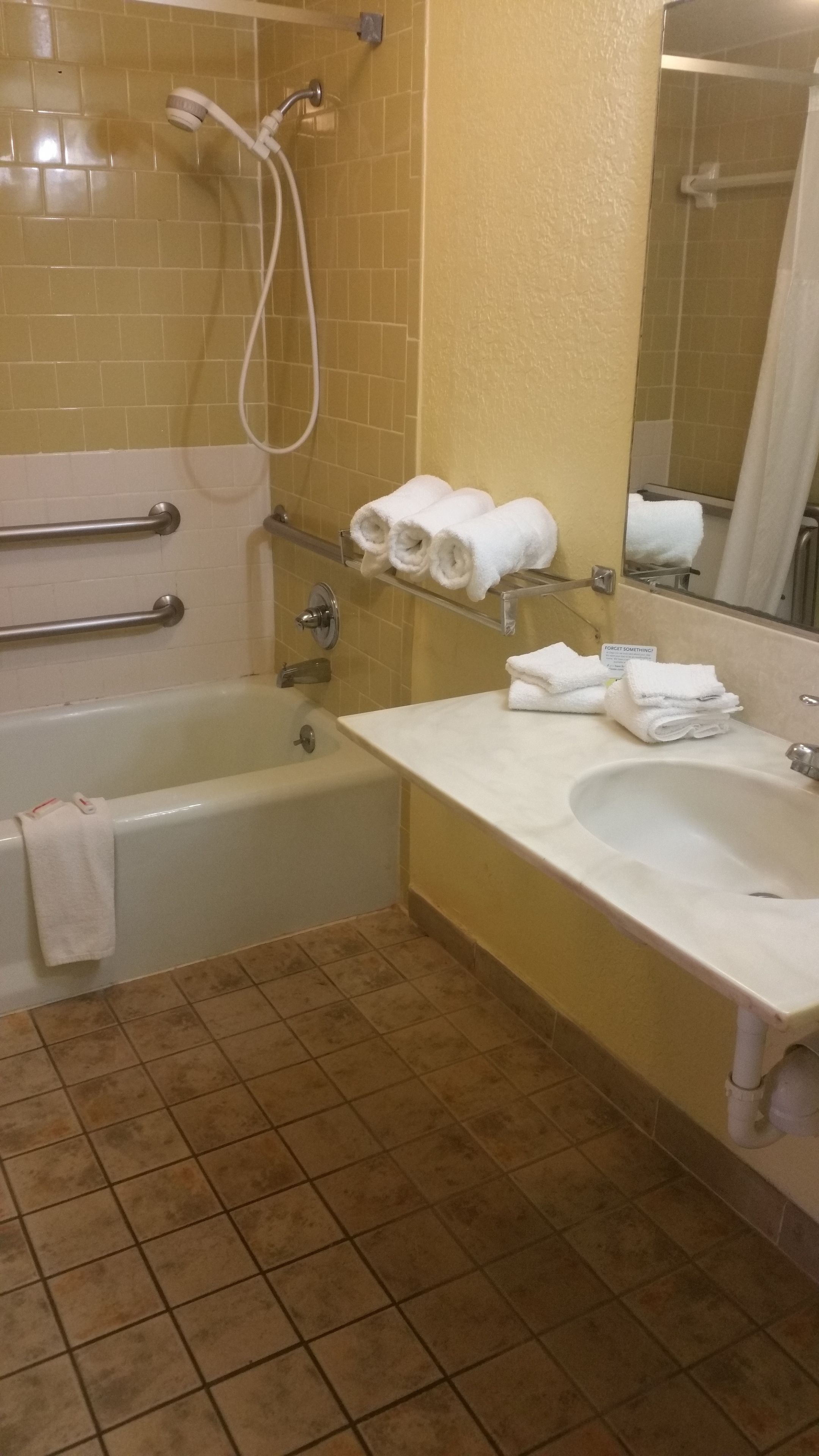 A bathroom with a bathtub, a sink, and a shower. There are towels on the sink and a towel hanging on the wall.