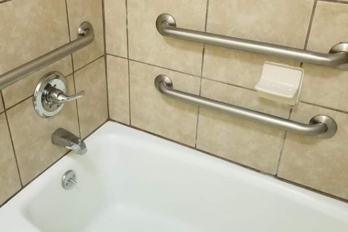 Un bagno con una vasca, un corrimano, un rubinetto e un portasapone.