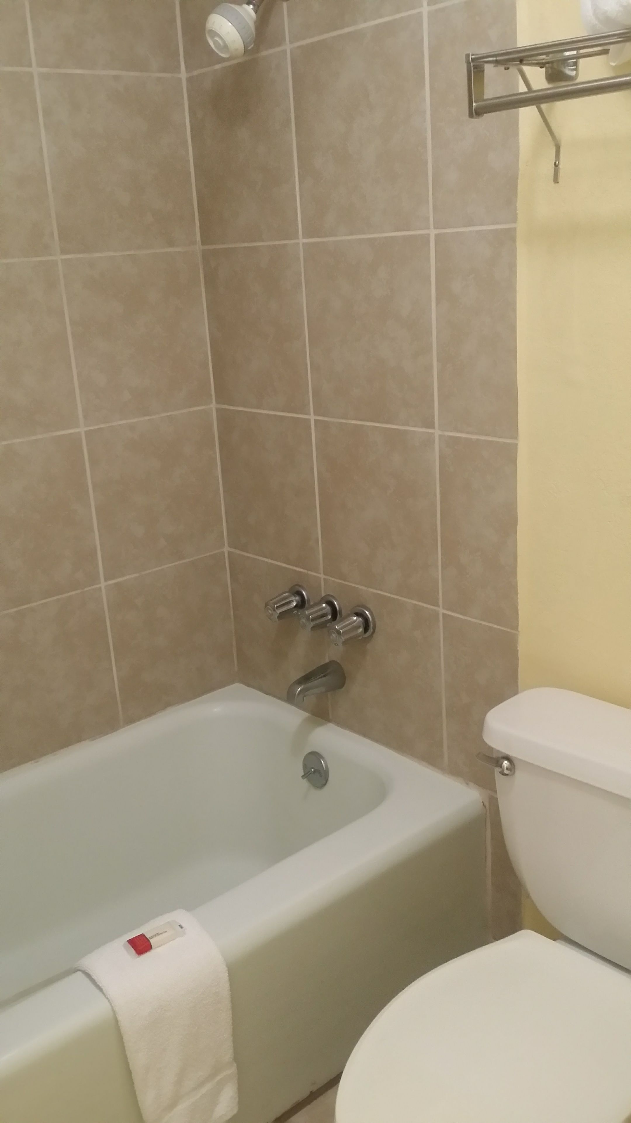 A bathroom with a bathtub, toilet, and a showerhead.