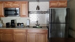 Una cocina con armarios de madera, un refrigerador de acero inoxidable, un microondas y un lavamanos.