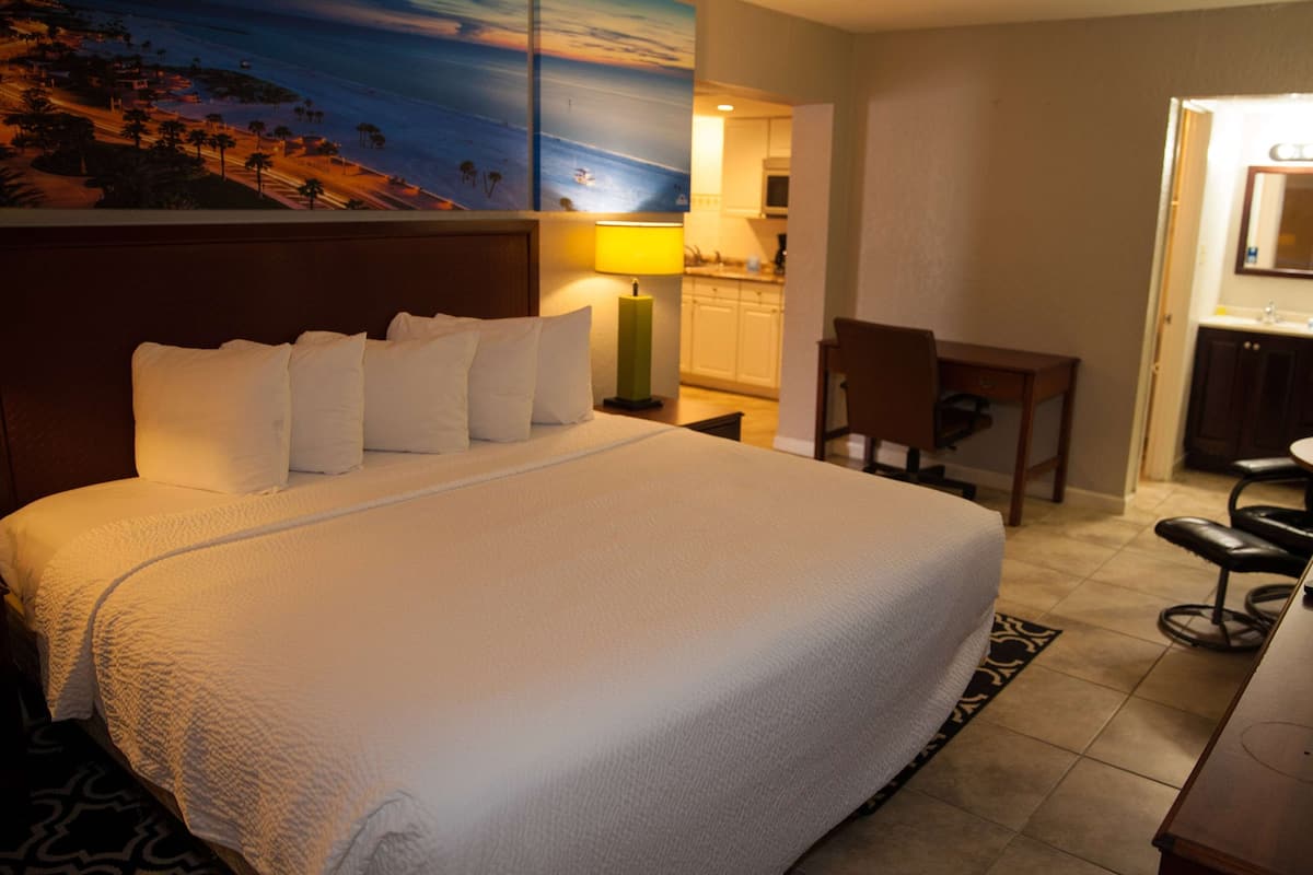Een hotelkamer met een groot bed, een bureau, een stoel, een lamp en een schilderij aan de muur.