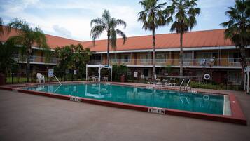 Un hotel con piscina, palmeras y techo de tejas rojas.