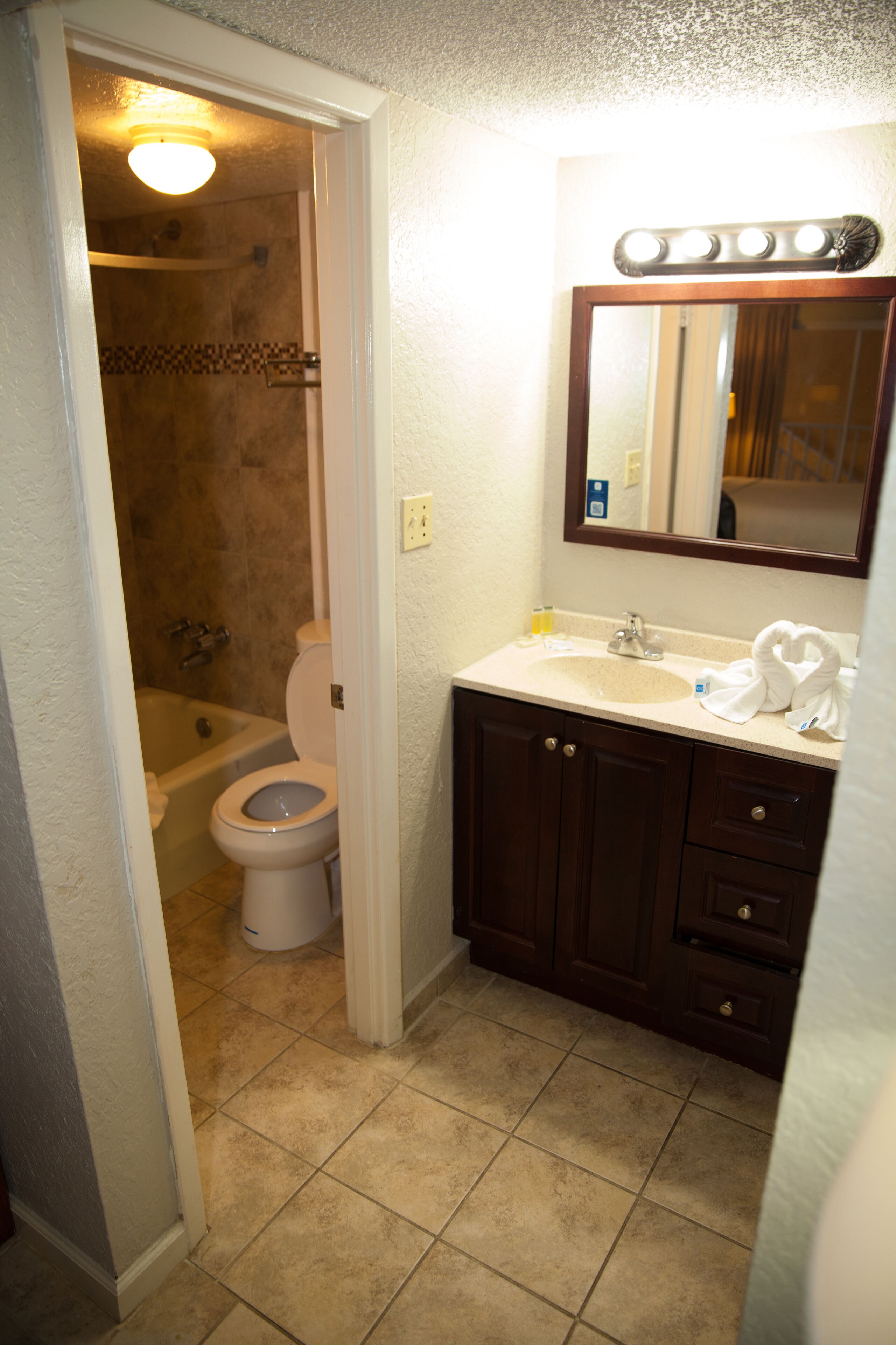 A bathroom with a toilet, sink, and mirror.