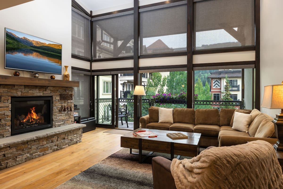 A living room with a fireplace, a large window, a sofa, and a coffee table.