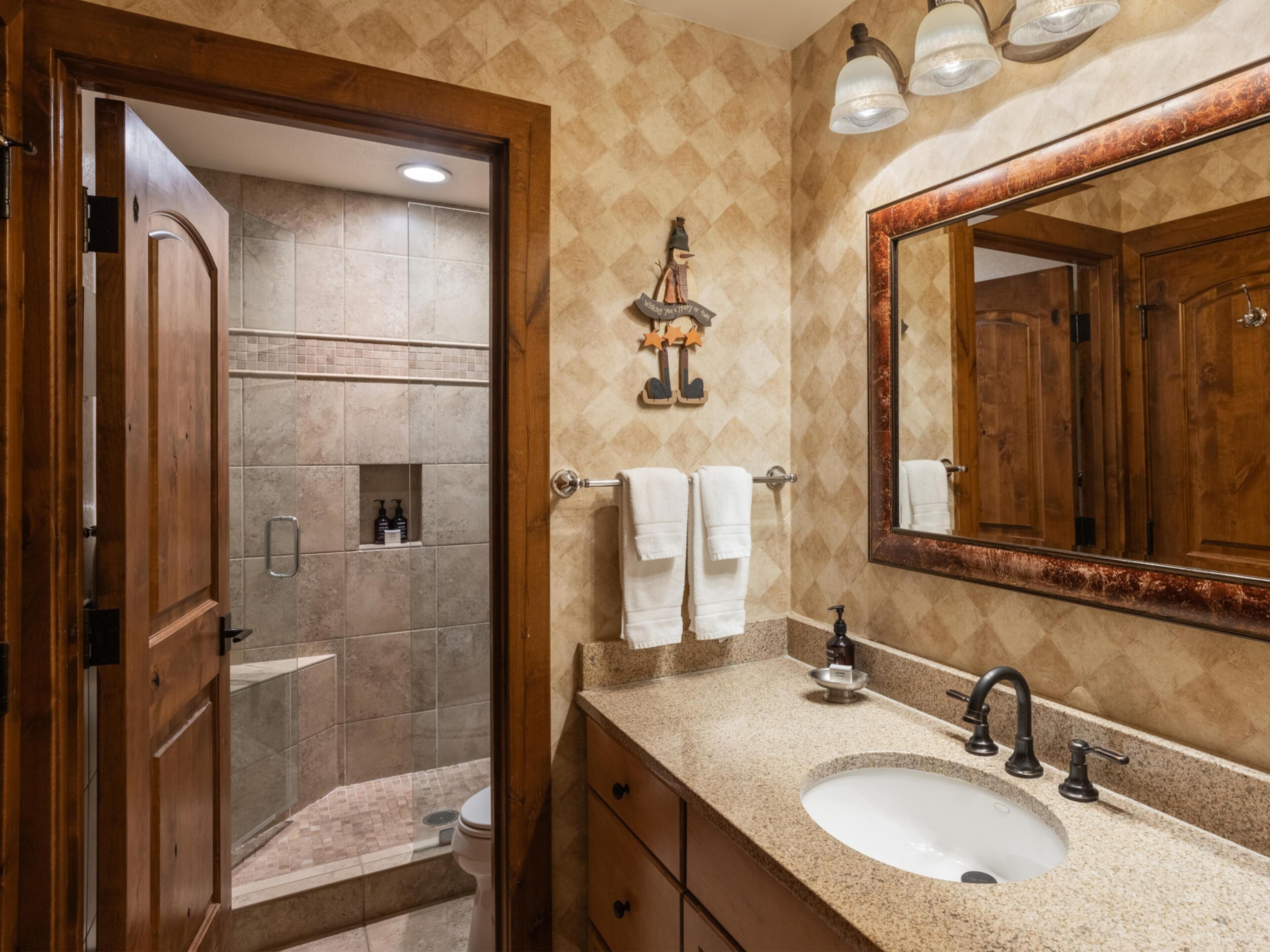Un baño con ducha, lavamanos y espejo.