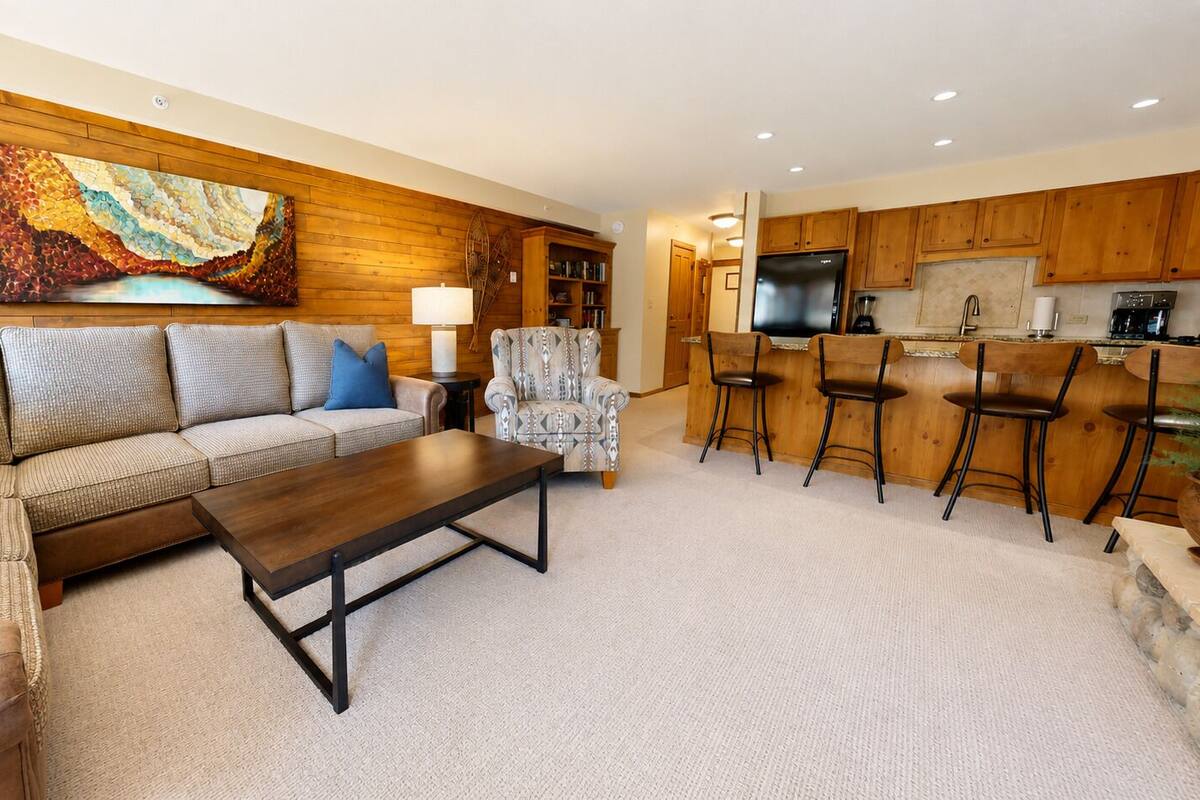 A living room with a sofa, armchair, coffee table, and a painting on the wall.