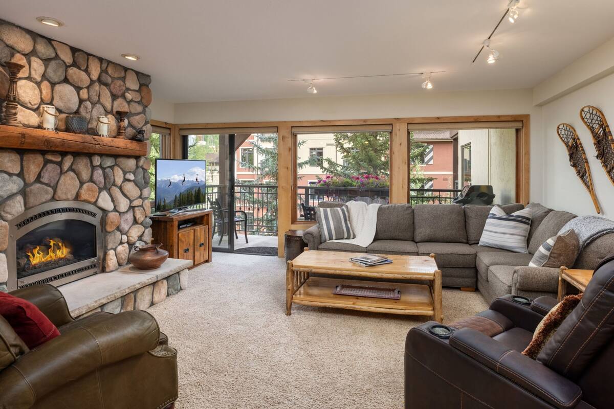 A cozy living room with a stone fireplace, a television, a sofa, and a coffee table.