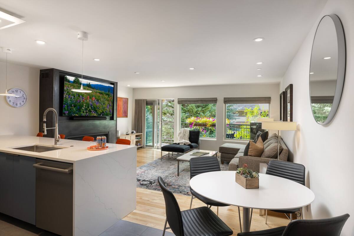 A modern kitchen with a built-in TV, a dining area with a round table, and a living space with a sofa and a coffee table.