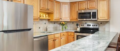 A modern kitchen with wooden cabinets, stainless steel appliances, and a granite countertop.