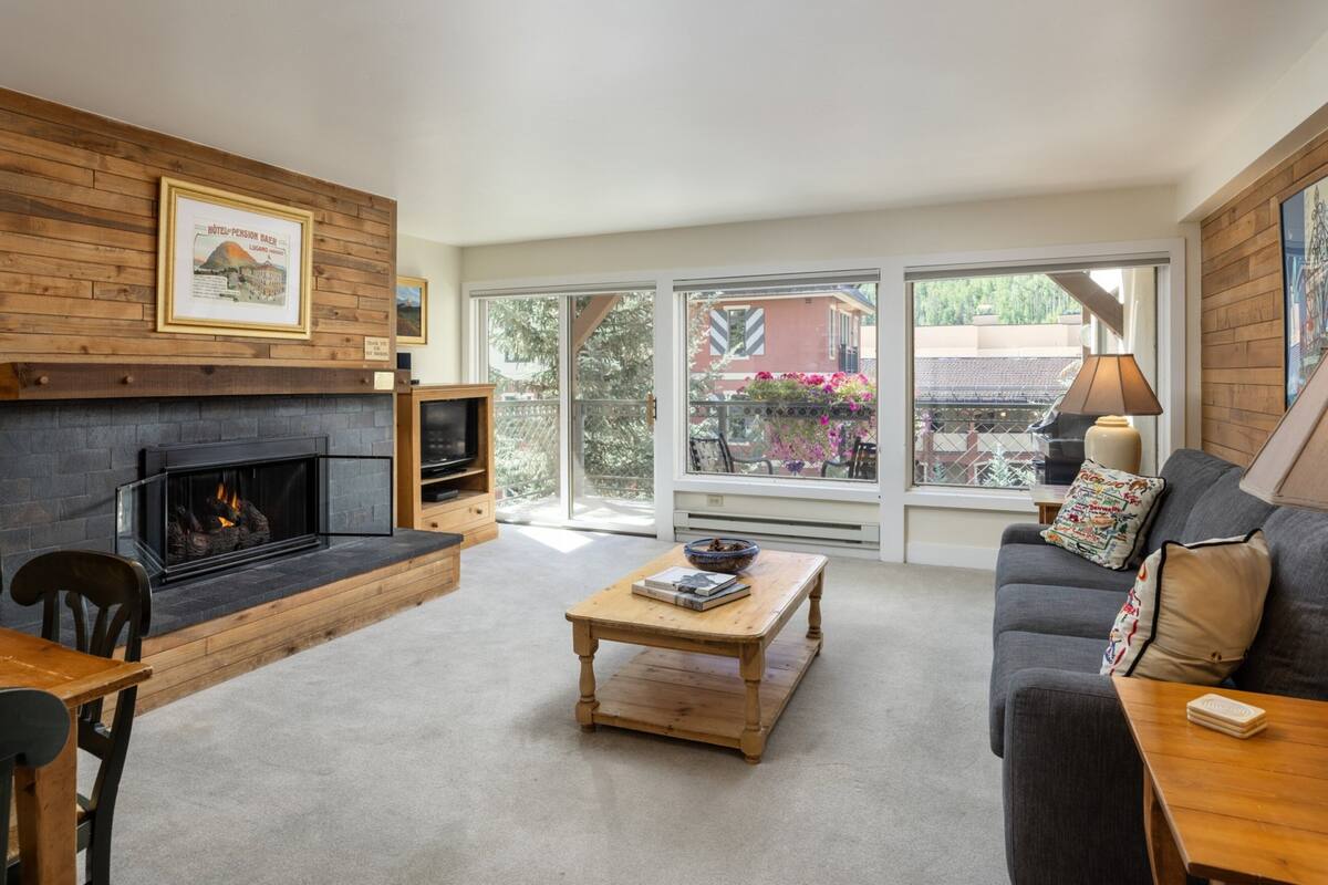 A living room with a fireplace, a sofa, a coffee table, and a TV stand.