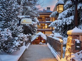 Un sendero cubierto de nieve que conduce a un edificio con un cartel que dice 'Montaneros'.