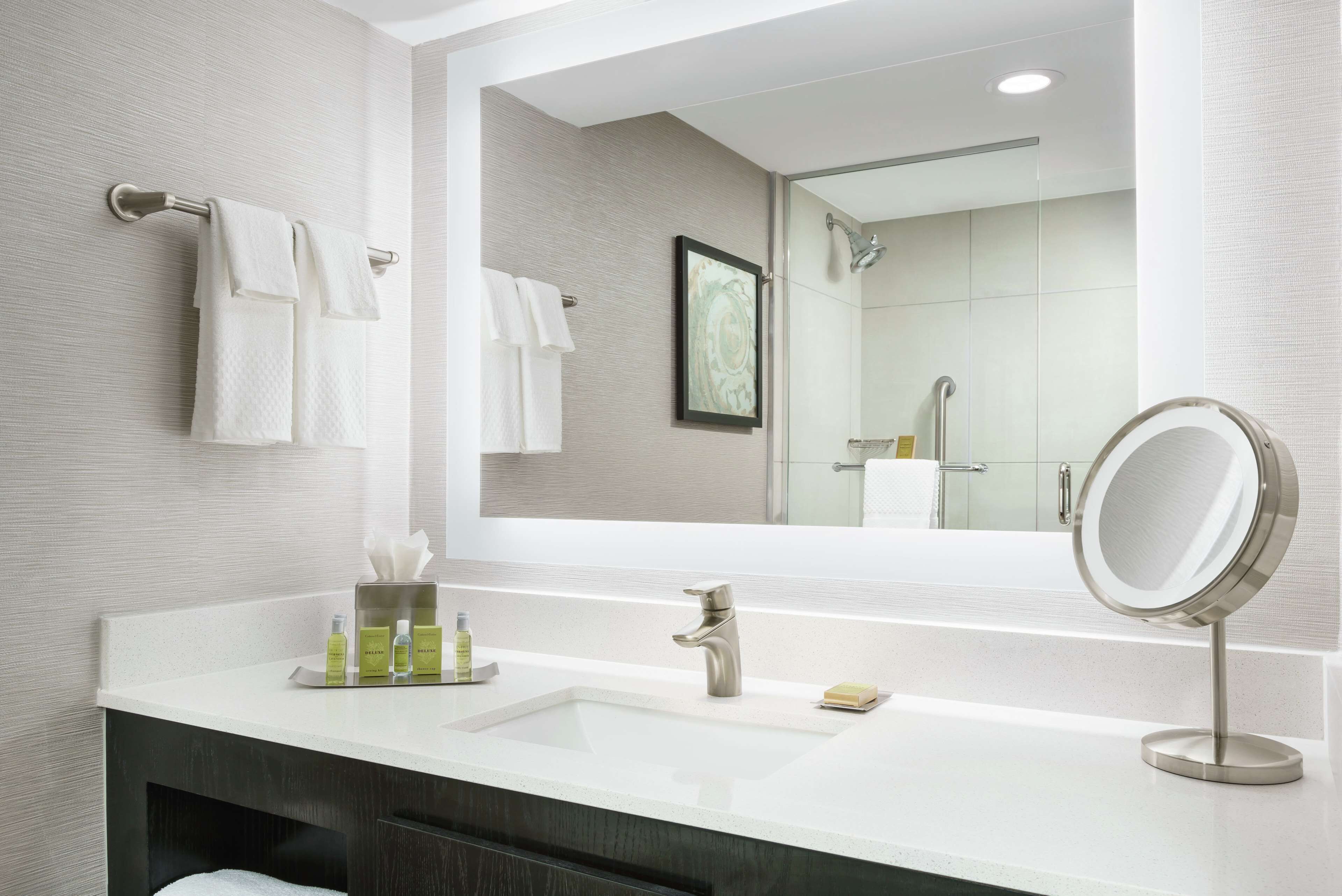 Un baño moderno con un espejo grande, un lavamanos y una ducha.