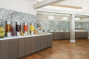 A buffet area with a variety of food items and a tiled backsplash.