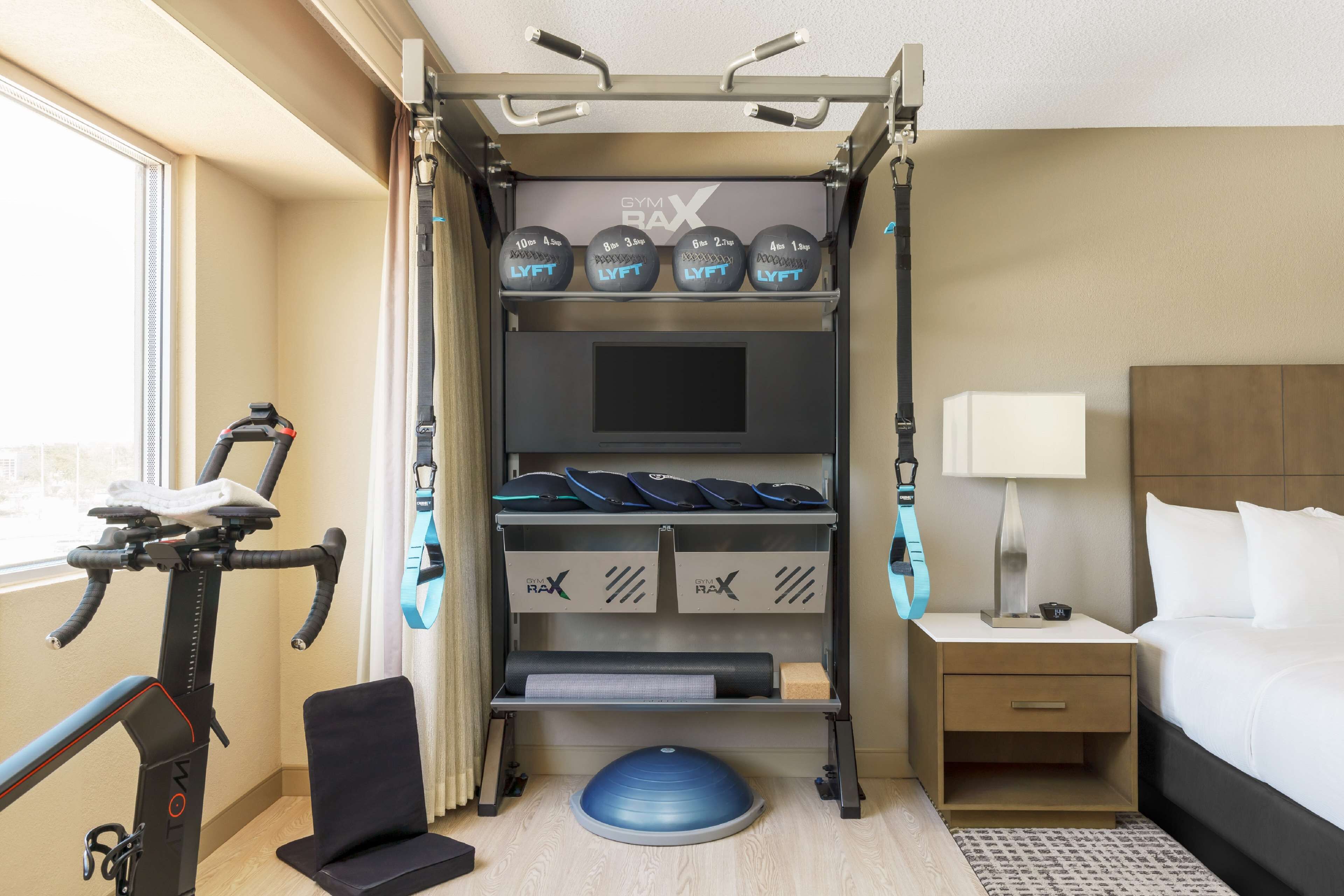 Habitación de hotel con barra de dominadas, discos de pesas, colchoneta de yoga y cinta de correr.