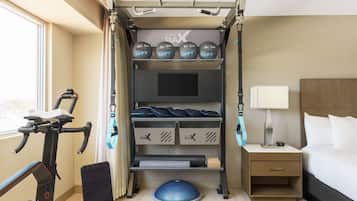 Habitación de hotel con barra de dominadas, discos de pesas, colchoneta de yoga y cinta de correr.