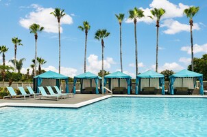 Una piscina al aire libre, sombrillas, sillones reclinables de piscina
