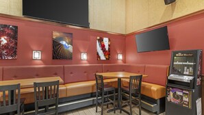 Un restaurante con área de mesas tipo cabina, una mesa con sillas y un jukebox.