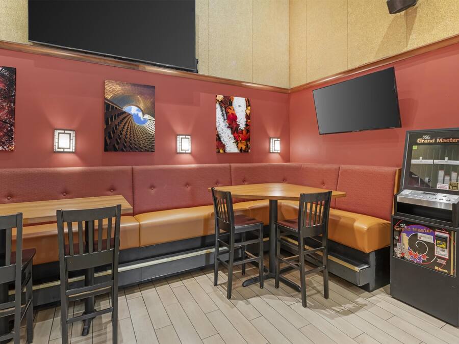 Een restaurant met een zithoek met kraamstoelen, een tafel met stoelen en een jukebox.