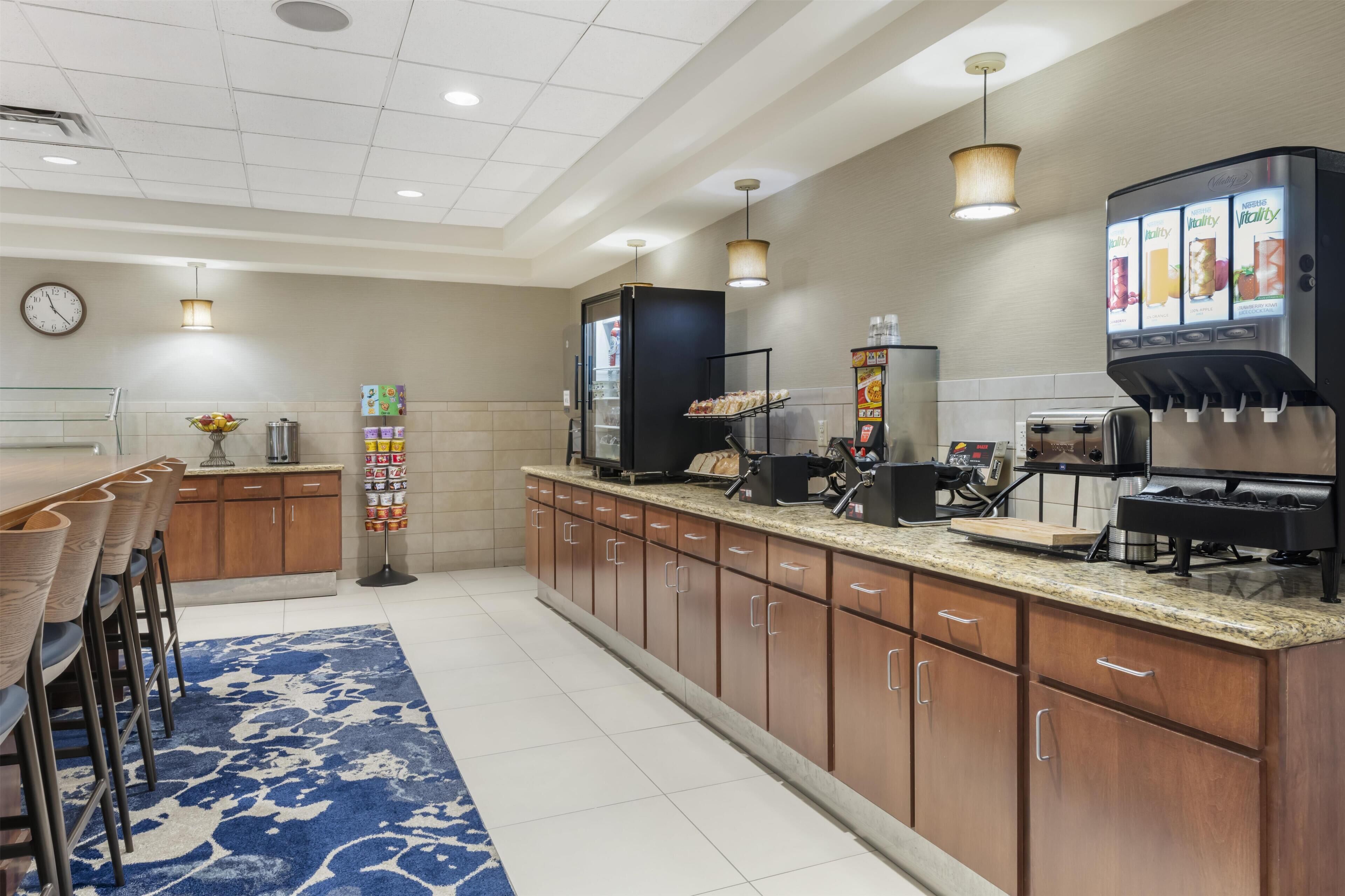 A modern kitchen with a long counter, a coffee machine, and a refrigerator.