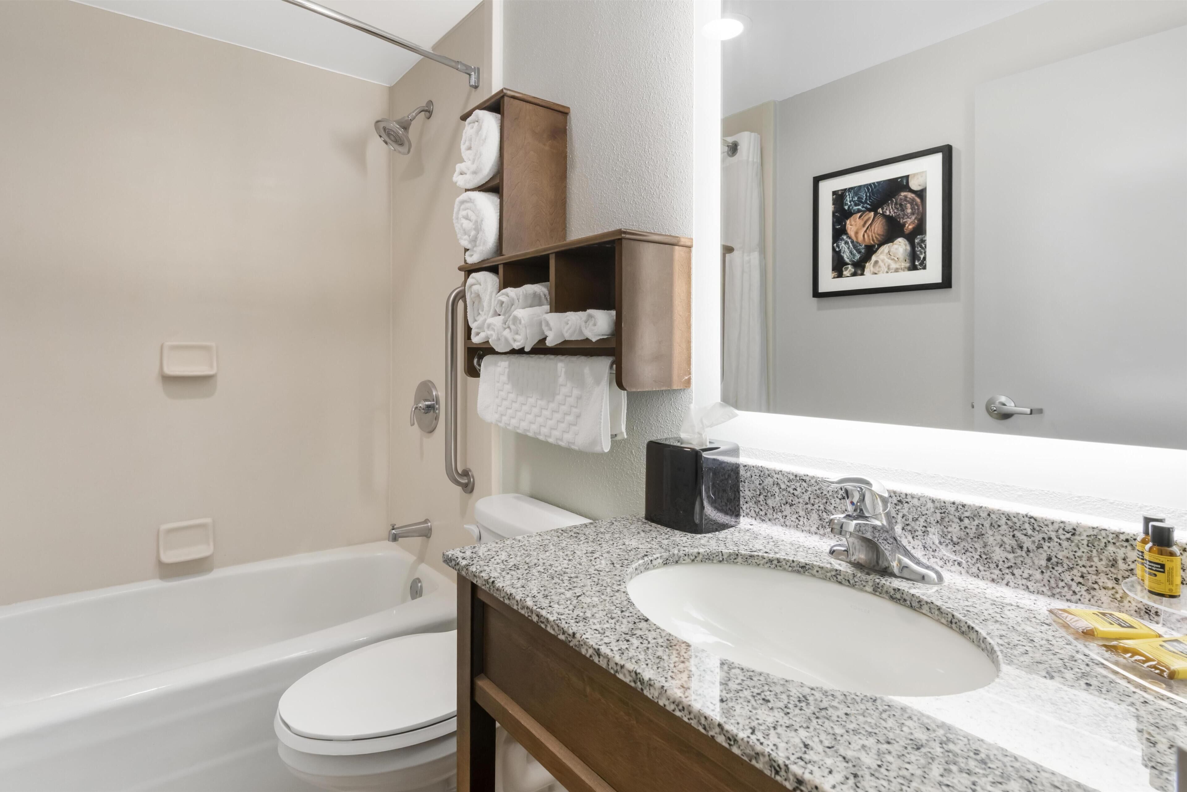 Un baño moderno con bañera, inodoro, lavamanos y espacio para toallas.