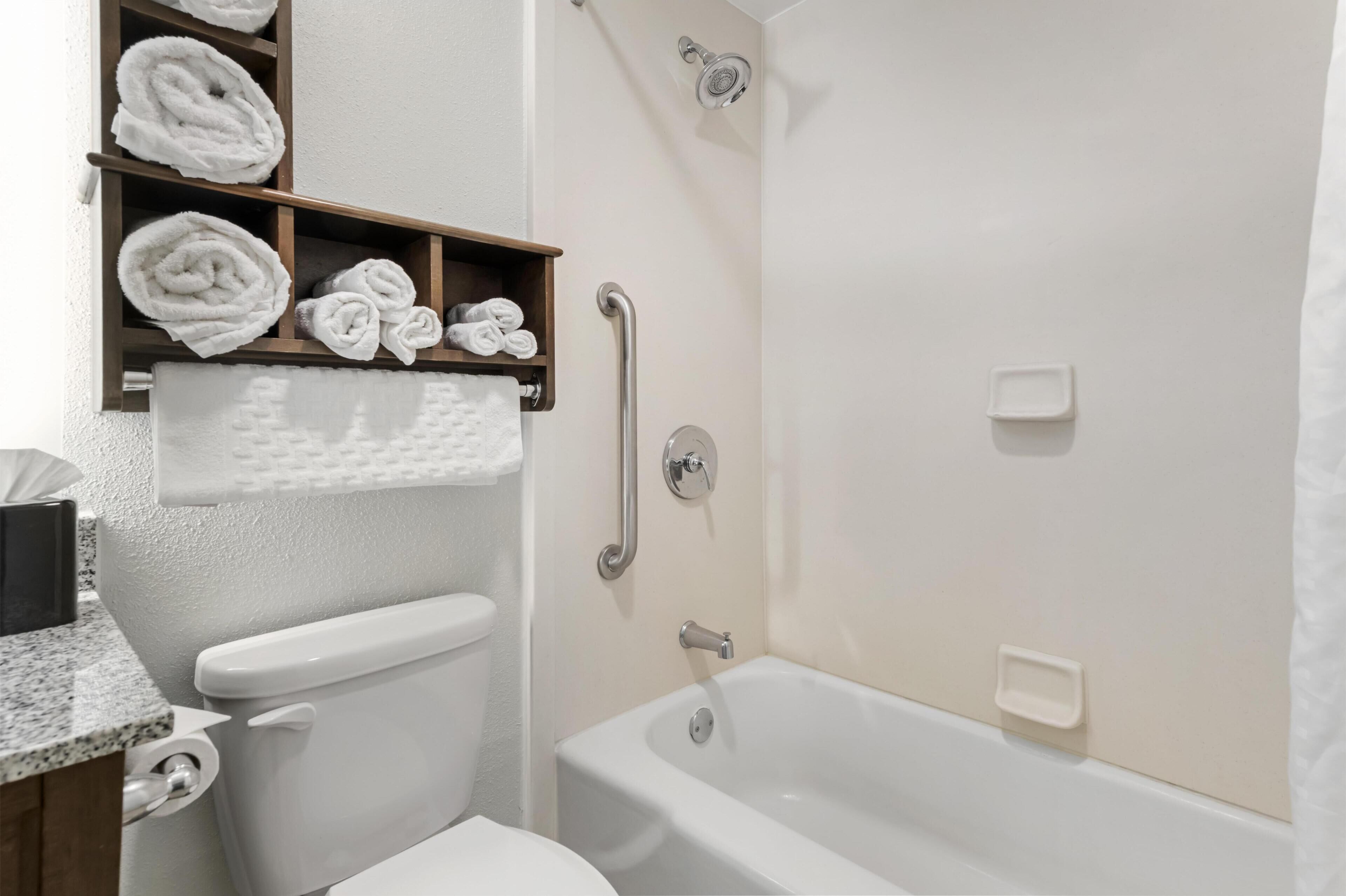 A bathroom with a toilet, a shower, and a bathtub. There are towels and a soap dish visible.