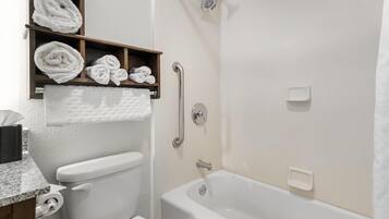 A bathroom with a toilet, a shower, and a bathtub. There are towels and a soap dish visible.
