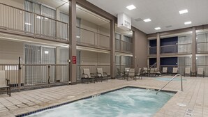 A hotel indoor pool area with multiple levels, seating arrangements, and a hot tub.