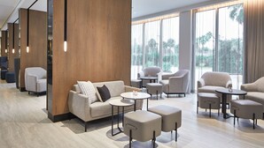 A modern hotel lobby with a sofa, armchairs, ottomans, and a coffee table. - AC Hotel by Marriott Orlando Lake Buena Vista (Orlando)