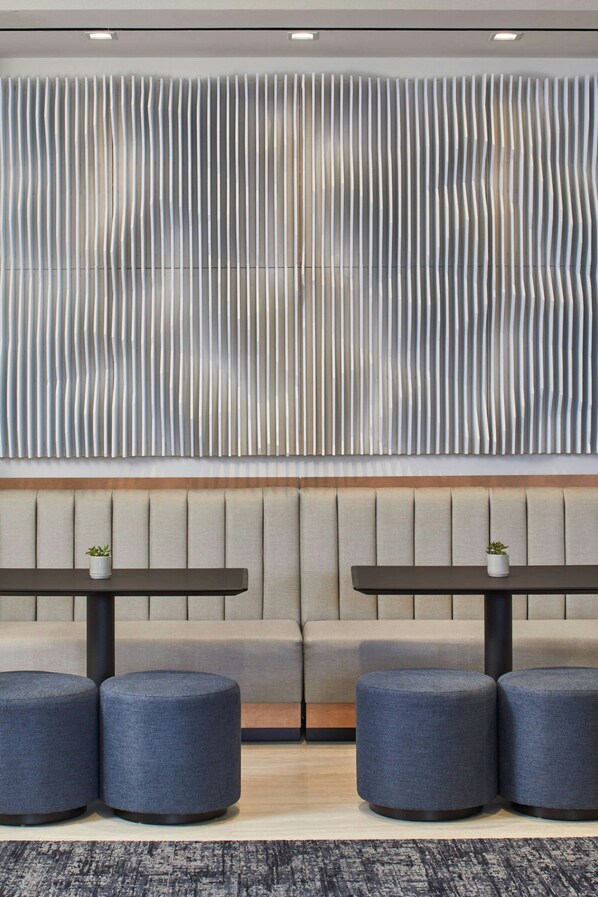 A modern lounge area with a sofa and two tables, each with a small plant.