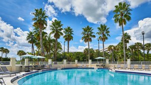 A swimming pool with lounge chairs and umbrellas, surrounded by palm trees. - AC Hotel by Marriott Orlando Lake Buena Vista (Orlando)
