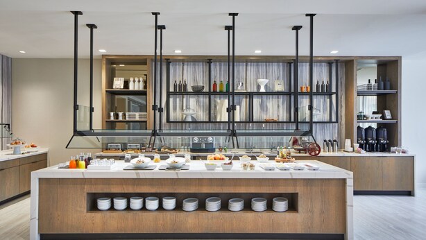 A modern kitchen with a central island, built-in shelves, and a variety of appliances and utensils. - AC Hotel by Marriott Orlando Lake Buena Vista (Orlando)