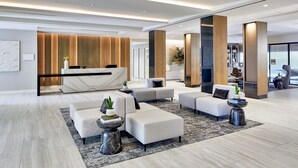A modern lobby with a reception desk, seating area, and a view of the city. - AC Hotel by Marriott Orlando Lake Buena Vista (Orlando)