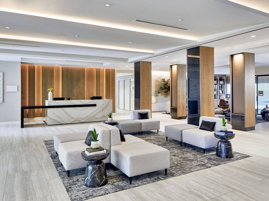 A modern lobby with a reception desk, seating area, and a view of the city.