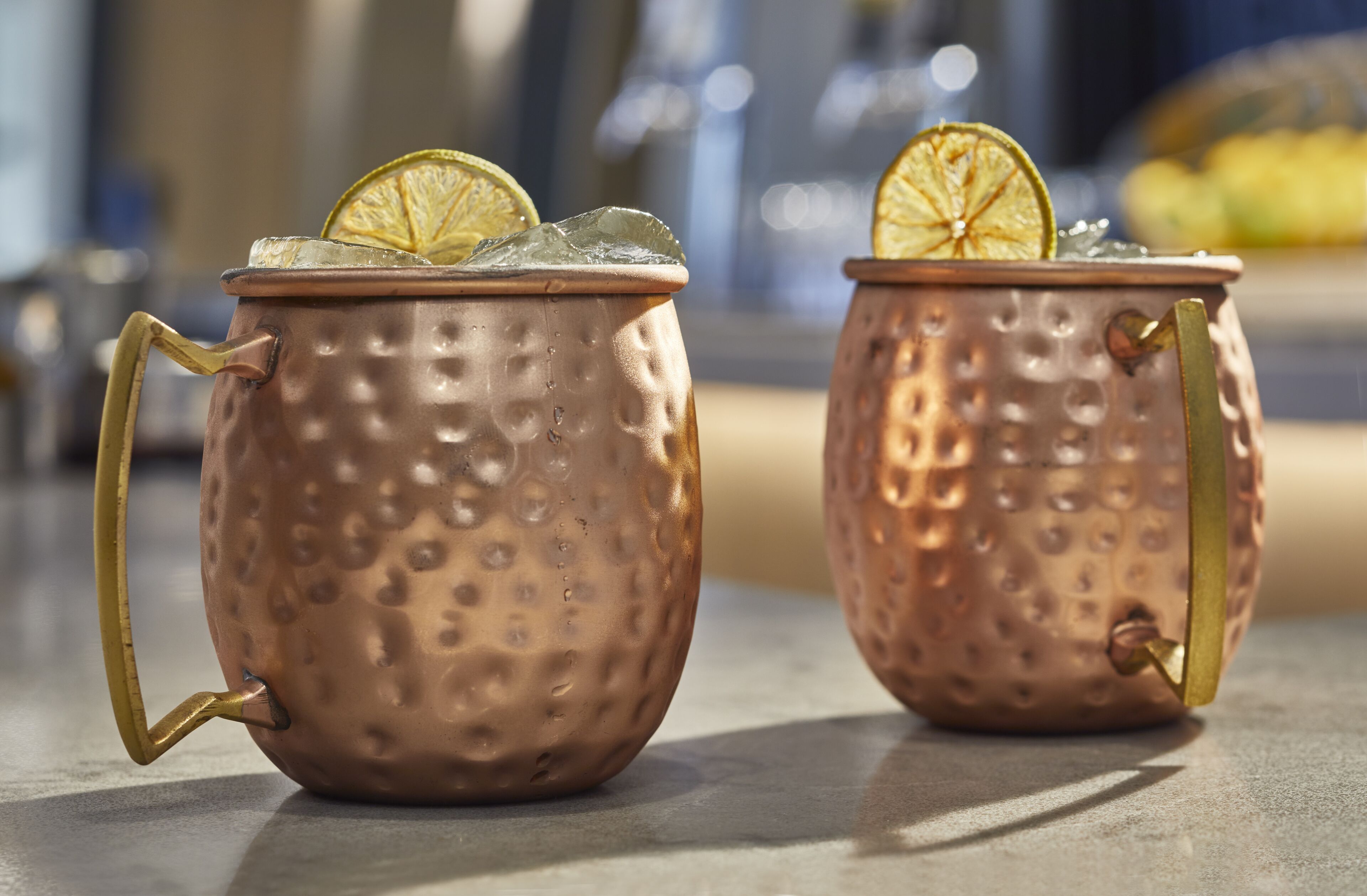 Two copper mugs with handles, each containing a slice of lime and ice.