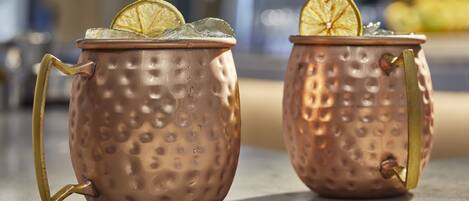 Two copper mugs with handles, each containing a slice of lime and ice.
