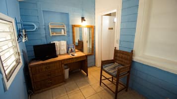 Een badkamer met blauwe wanden, een houten wastafelmeubel, een stoel, een spiegel en een toilet.