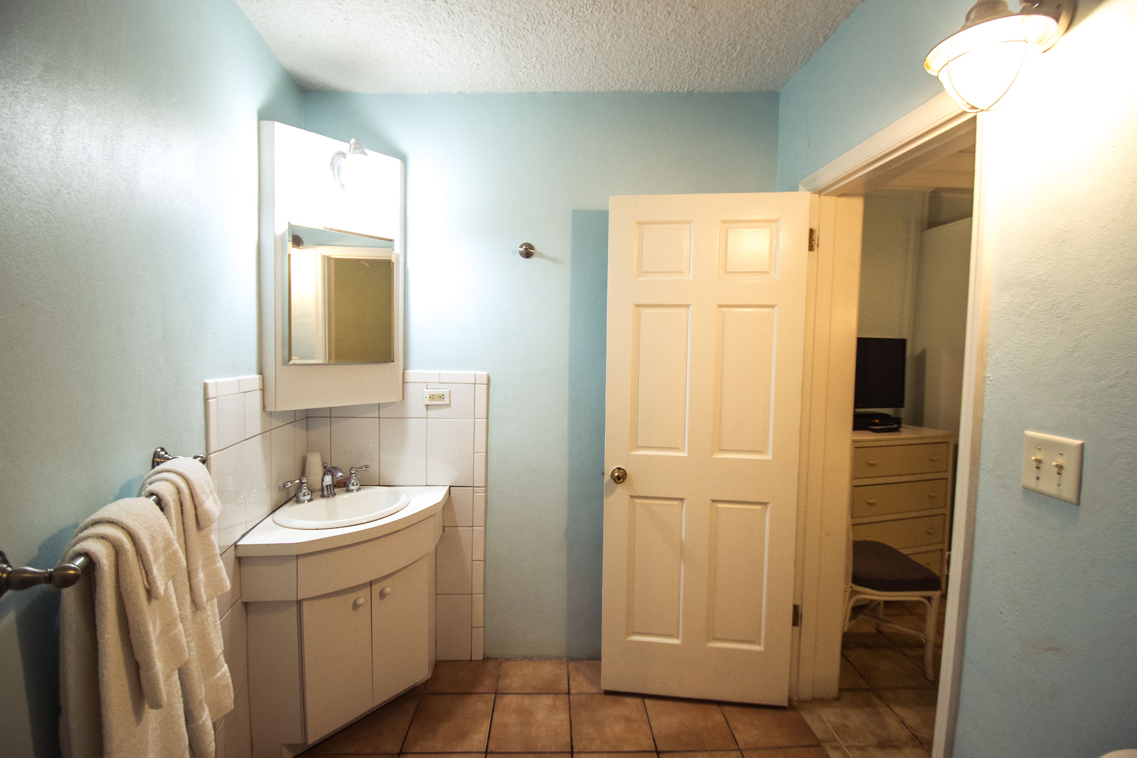 A bathroom with a sink, mirror, and towel rack.